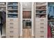 Walk-in closet with custom shelves and drawers, leading to a separate laundry area at 3214 Heron Lakes Pkwy, Berthoud, CO 80513