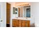Bathroom with double sinks, light wood vanity, large mirror, and a view of the shower/tub area at 10486 Cheetah Winds, Lone Tree, CO 80124