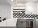 Modern kitchen features updated appliances, grey and white cabinets, quartz countertops, and decorative tile backsplash at 345 Fillmore # 407, Denver, CO 80206
