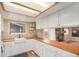 Bright kitchen features white cabinets, butcher block countertops, and a view to the living room fireplace at 8970 Garland Ct, Westminster, CO 80021