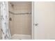 Shower stall features neutral tiling with a decorative accent band and a playful shower curtain at 8970 Garland Ct, Westminster, CO 80021