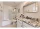 Bright bathroom featuring a shower over tub, granite countertop, and decorative mirror at 6108 S Harvest Ct, Aurora, CO 80016