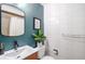 Clean bathroom with white tiles, a modern vanity, and a teal accent wall at 1398 S Fairfax St, Denver, CO 80222