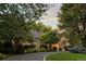 Elegant home featuring lush landscaping, a circular driveway, and warm exterior lighting at 1350 E Greenwood Ln, Greenwood Village, CO 80121