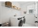 Bright laundry room with a front load washer and dryer, shelf, window, and decorative hanging plant at 12270 W 57Th Ave, Arvada, CO 80002