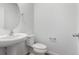 Bright white half bath featuring pedestal sink, toilet, and towel bar at 5783 N Jericho Way, Aurora, CO 80019