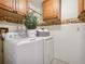 Bright laundry room with upper cabinets, sunflower wallpaper border and modern white appliances at 6490 S Pontiac Ct, Centennial, CO 80111