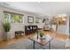 Stylish living room with hardwood floors, large windows, modern furniture, and staircase to the kitchen at 6490 S Pontiac Ct, Centennial, CO 80111