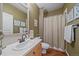 Cozy bathroom with an integrated shower, single sink vanity, and decorative floral artwork at 12957 W 78Th Cir, Arvada, CO 80005