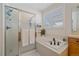 Bathroom featuring a glass enclosed shower and a separate soaking tub beneath a bright window at 12957 W 78Th Cir, Arvada, CO 80005