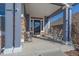 Inviting front porch featuring rocking chairs, stone pillars, and a stylish entrance door at 12957 W 78Th Cir, Arvada, CO 80005