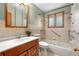Updated bathroom features vanity with solid surface countertop, tiled walls, and tub at 7742 W Florida Dr, Lakewood, CO 80232