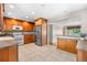 Bright and functional kitchen featuring wood cabinets, tile flooring, stainless steel refrigerator, and an open layout at 7742 W Florida Dr, Lakewood, CO 80232