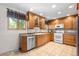 Well-lit kitchen featuring wood cabinets, stainless steel appliances, tile floor, and granite countertops at 7742 W Florida Dr, Lakewood, CO 80232