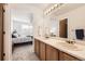Bright bathroom with double sinks, wood cabinets, and a view of bedroom at 3734 Licorice Trl, Castle Rock, CO 80109