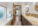 Bathroom with dual sinks, custom vanity, tiled floors and countertops, a separate tub, and an open door to a bedroom at 4525 King St, Denver, CO 80211