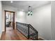 Hallway featuring beautiful hardwood floors, decorative iron railing, and a unique hanging light fixture at 4525 King St, Denver, CO 80211