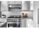 Close-up of kitchen featuring stainless steel stove, modern vent hood, and decorative backsplash at 4525 King St, Denver, CO 80211