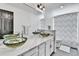 Bathroom featuring dual vessel sinks, a large mirror, and a patterned shower curtain at 11209 Quivas Loop, Denver, CO 80234