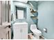 Stylish powder room with modern vanity, floating shelves, and soft aqua walls at 11209 Quivas Loop, Denver, CO 80234