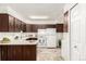 Well-lit kitchen with dark wood cabinets, white appliances, and a patterned rug at 3450 S Poplar St # 109, Denver, CO 80224