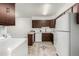 Compact kitchen with dark wood cabinets, white appliances, and washer hookups at 3450 S Poplar St # 109, Denver, CO 80224