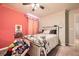 Cozy bedroom features a ceiling fan, plush carpets, and a brightly decorated pink accent wall at 1867 Homestead Dr, Fort Lupton, CO 80621