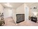 Bright hallway features carpeted flooring, white trim, neutral-colored walls and a black railing; modern design with ample natural light at 1867 Homestead Dr, Fort Lupton, CO 80621