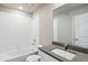 Bathroom with tub and shower combo, white tile, white cabinets and gray countertops at 3003 Pershing St, Strasburg, CO 80136