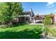 Large backyard featuring mature trees, a wooden deck, a covered area, and lush green lawn at 6150 Reed St, Arvada, CO 80003