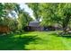 Large backyard with a storage shed and a well-manicured lawn surrounded by mature trees at 6150 Reed St, Arvada, CO 80003