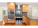 Kitchen with stainless steel oven, hood, and microwave, wooden cabinets, countertop, and hardwood floors at 6150 Reed St, Arvada, CO 80003