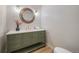 Stylish powder room with a green vanity and a round mirror at 7910 E Bethany Pl, Denver, CO 80231