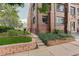 Brick apartment building exterior with garden beds and secure wrought-iron fencing at 1060 N Washington St # 1A, Denver, CO 80203