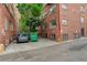 Back parking lot with a car, trash bin, and brick building at 1060 N Washington St # 1A, Denver, CO 80203