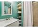 Bathroom with updated vanity, mirror, shelves, and a shower with a white curtain at 6327 S Emporia Cir, Englewood, CO 80111
