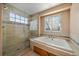 Bright bathroom featuring a tiled walk-in shower and soaking tub beneath a window at 10900 Parker Vista Rd, Parker, CO 80138