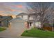 Charming two-story home with a well-manicured lawn, attached garage, and delightful curb appeal, set against a colorful sunset at 10900 Parker Vista Rd, Parker, CO 80138