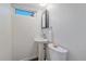 Modern half bathroom with a pedestal sink, toilet, and framed mirror, complete with fixtures and lighting at 3738 Miller Ct, Wheat Ridge, CO 80033