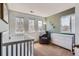 Light-filled bedroom showcases a white crib, dresser, chair, and three windows at 6853 W Rockland Pl, Littleton, CO 80128