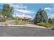 Beautifully landscaped home with a lush green lawn, mature trees, and a paved driveway leading to the garage at 10985 Ambush Rock, Littleton, CO 80125