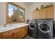 Laundry room with a utility sink, upper cabinets, and a large window with a view of the outdoors at 10985 Ambush Rock, Littleton, CO 80125