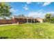 Spacious backyard with lush green grass, privacy fence, and brick home exterior with covered patio at 5593 E Center Ave, Denver, CO 80246