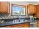 Kitchen features a stainless steel sink with tiled backsplash and wooden cabinetry at 5593 E Center Ave, Denver, CO 80246