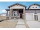 Inviting front entrance with stone accents, gray siding, and a well-maintained landscaped approach to the front door at 17673 Brass Buckle Way, Monument, CO 80132