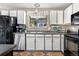 Kitchen featuring stainless steel appliances, white cabinets, and window with hanging lights at 8612 S Everett Ct, Littleton, CO 80128