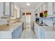 Efficient kitchen with vintage blue cabinets and white appliances with an adjacent dining area at 1425 S Newport St, Denver, CO 80224