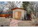 View of a backyard shed with a stone pathway, a whimsical bird bath, and mature foliage at 1425 S Newport St, Denver, CO 80224