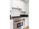 Close-up view of a Wolf stainless steel oven and cooktop with white tile backsplash at 1767 S Sherman St, Denver, CO 80210