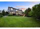 Spacious backyard featuring a large lawn, mature trees, a deck, and a walk-out basement at 6175 Puma Sands, Lone Tree, CO 80124